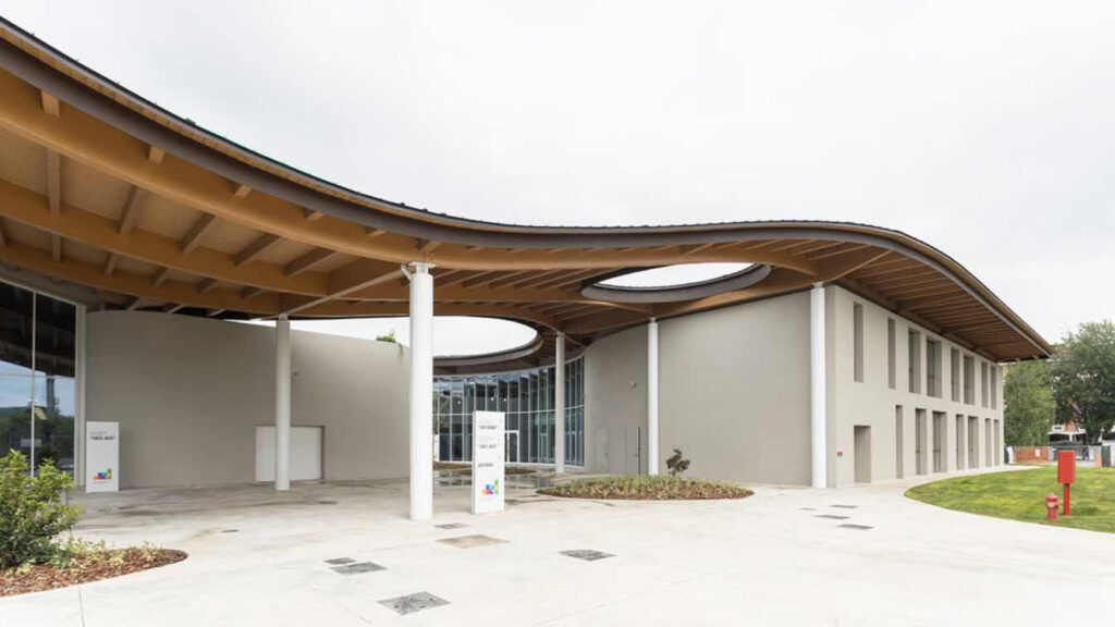 Kampus, bílá budova, oblá dřevěná střecha