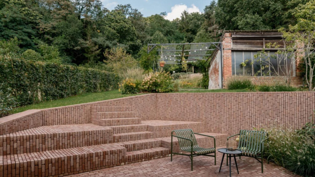 Cihlové schody a opěrné zdi na terase obložené vertikálně kladenými světle červenými cihlami – teplá textura navozuje hravý a útulný vzhled.