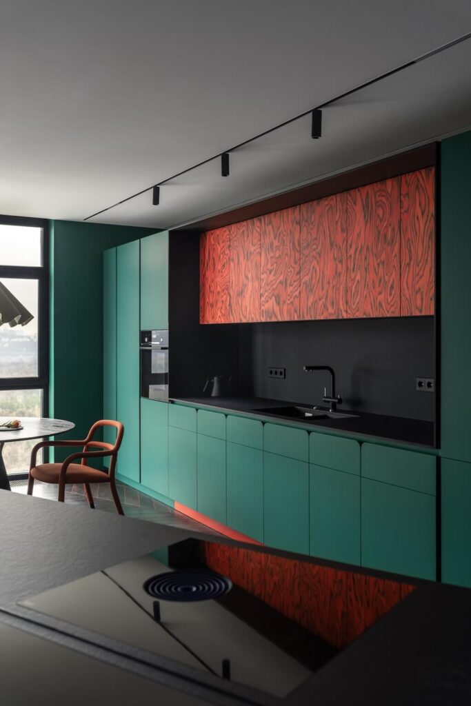 Kuchyň s betonovým pilířem, uměleckým obrazem a zelenými dvířky z dýhy Alpi